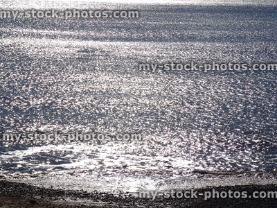 Stock image of seaside waves sparkling, beach backlit by morning sun