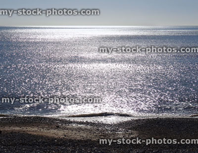 Stock image of backlit seaside with sun shining on sea, sparkling-water