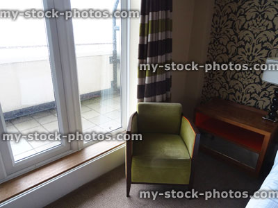 Stock image of green armchair in bedroom suite, next to bed / balcony window