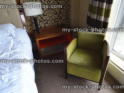 Stock image of green armchair in bedroom suite, next to bed / balcony window