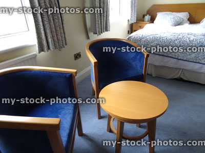 Stock image of two blue cushioned, wooden curved bedroom armchairs / double bed, chairs, bucket seat, round table