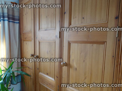 Stock image of triple wooden pine wardrobe doors in bedroom, waxed