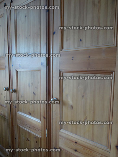 Stock image of triple wooden pine wardrobe doors in bedroom, waxed