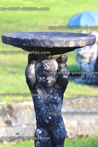 Stock image of stone statue birdbath with boy cherub figure / statuette