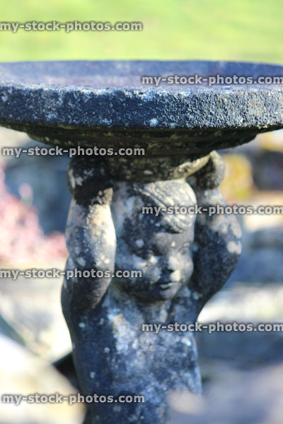 Stock image of boy statue stone birdbath, cherub figurine holding dish