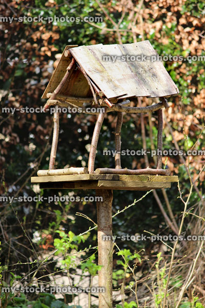 Stock image of homemade rustic birdtable, wooden shingle roof, feeding birds