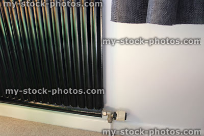 Stock image of a single bedroom radiator painted black, white wall