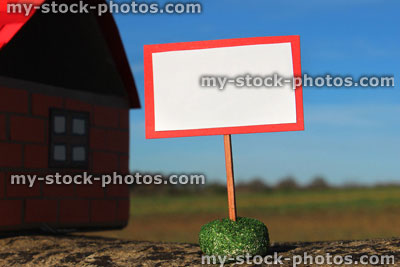 Stock image of cardboard model house, blank sign / signpost / placard, real estate, estate agent, property market