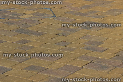 Stock image of golden block paving driveway, paved manhole drain cover