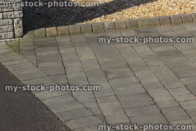 Stock image of raised edging bricks along grey block paved driveway