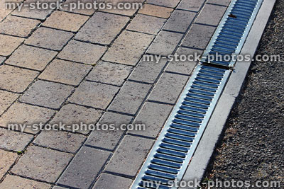 Stock image of linear drainage channel and grate by block paving driveway