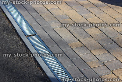 Stock image of metal drainage channel in between block paved driveway and pavement