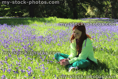 Stock image of girl with long hair lying down, field of bluebell flowers