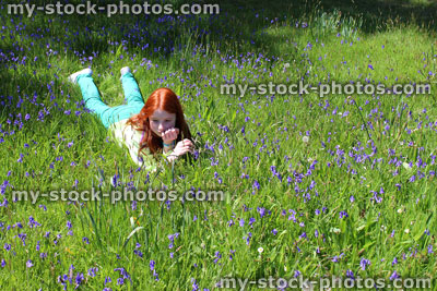 Stock image of child with red hair lying down, field of bluebell flowers