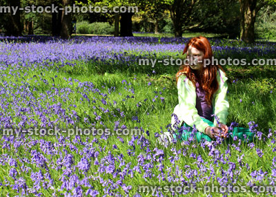 Stock image of girl with red hair sitting in field of bluebell flowers