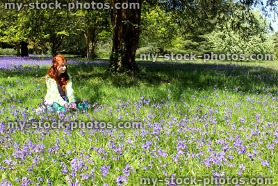 Stock image of child with long red hair sitting, field of bluebell flowers