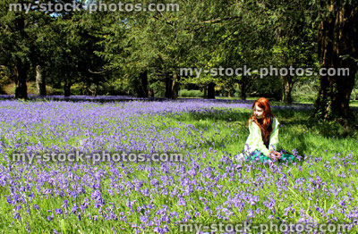 Stock image of girl with long red hair sitting, field of bluebell flowers