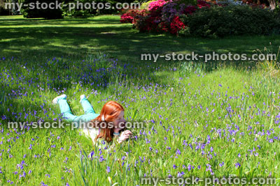 Stock image of girl with long red hair lying, field of bluebell flowers
