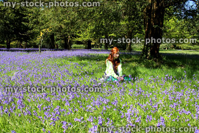 Stock image of girl with long hair sitting in field of bluebell flowers