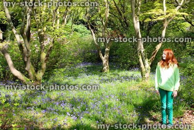 Stock image of girl standing next to Japanese maples and bluebells