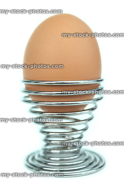 Stock image of boiled egg, silver chrome metal, coiled spring egg cup