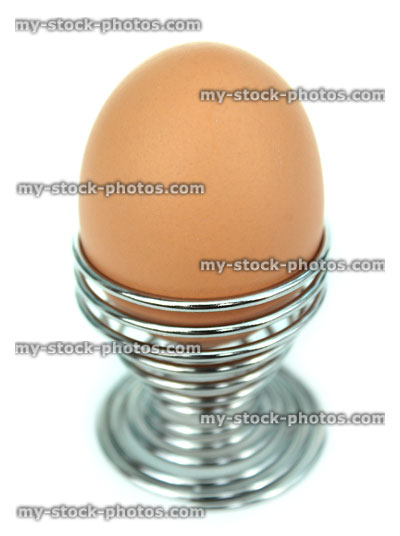 Stock image of boiled egg, chrome metal, coiled spring egg cup, looking down