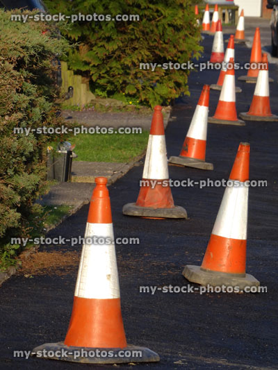 Stock image of orange and white bollards on tarmac pavement / sidewalk
