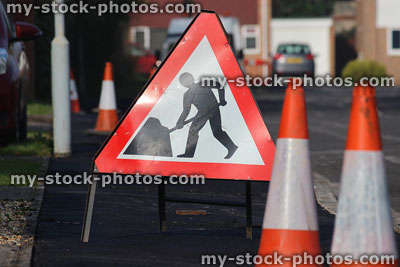 Stock image of triangular road sign 'Men at Work', warning bollards