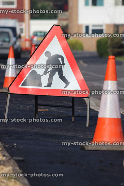 Stock image of newly resurfaced tarmac pavement with traffic cones, warning sign