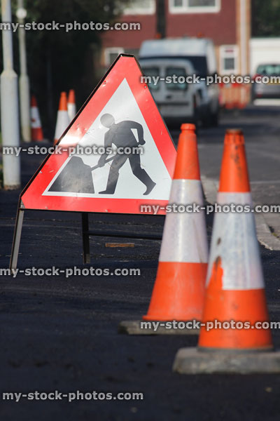 Stock image of housing estate with new tarmac pavement, road sign, traffic cones