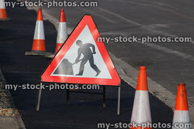 Stock image of road sign with traffic cone bollards on pavement