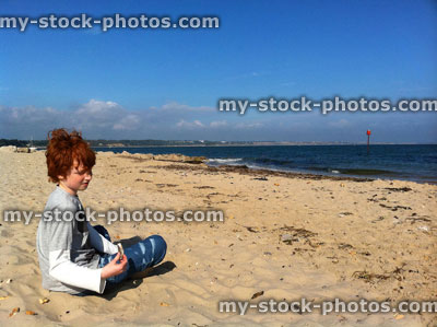 Stock image of boy sat on a remote beach (close up)