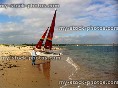 Stock image of red head teenage boy walking past a boat with a red sail