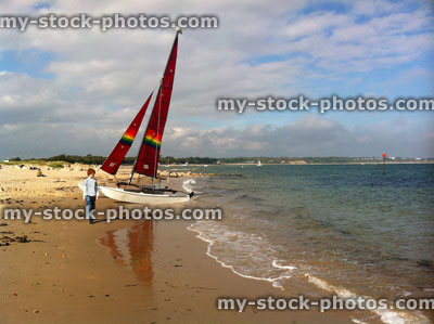 Stock image of red head teenage boy walking past a boat with a red sail