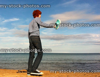 Stock image of red head teenage boy stood on beach facing the sea