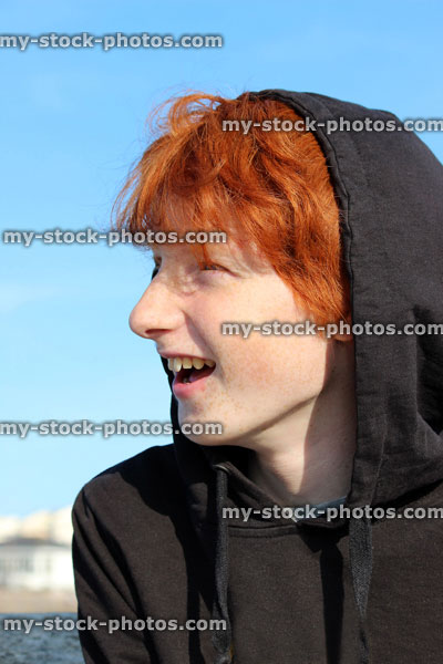 Stock image of red hair teenage boy wearing black hoodie, youth smiling and laughing