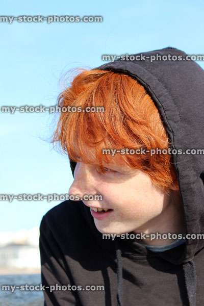 Stock image of red hair teenage boy wearing black hoodie, youth smiling and laughing