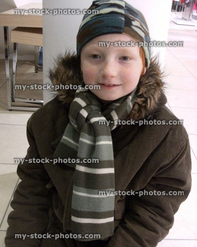 Stock image of young boy in his green winter coat, hat and scarf