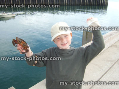 Stock image of red headed boy holding a crab
