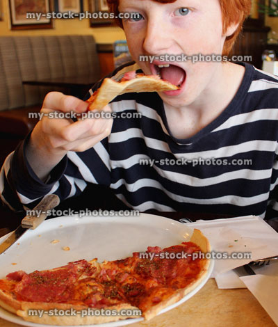 Stock image of boy eating homemade pepperoni pizza in Italian restaurant