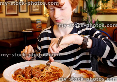 Stock image of boy eating spaghetti meatballs pasta in Italian restaurant