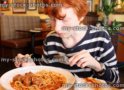 Stock image of boy eating spaghetti meatballs pasta in Italian restaurant