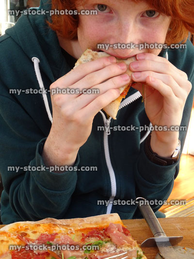 Stock image of teenage boy eating homemade pizza in Italian restaurant
