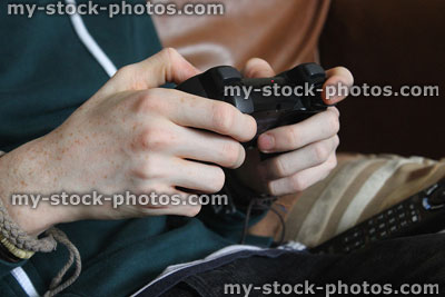 Stock image of boy playing computer video game, wireless gaming controller