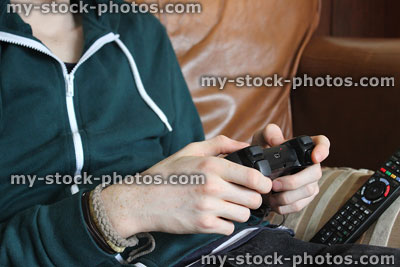 Stock image of boy sitting on sofa, playing video game, wireless controller