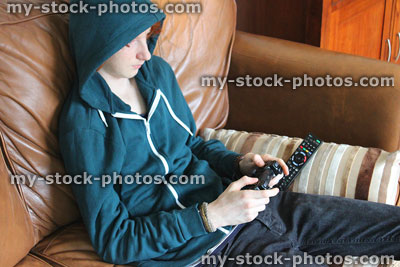Stock image of boy wearing blue hoodie, playing on video game console