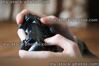 Stock image of boy playing PlayStation computer video games, cordless wireless controller
