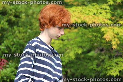 Stock image of teenage boy gardening, brushing pathway in garden, chores