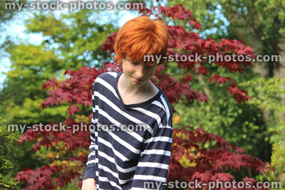 Stock image of teenage boy gardening, brushing pathway in garden, chores