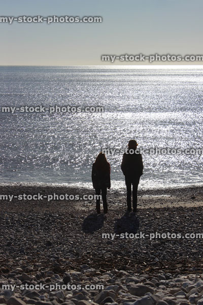 Stock image of children silhouettes on sunny beach against sea / sky
